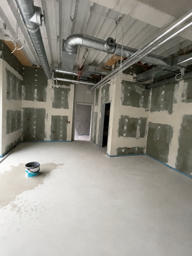 Raum im Innenausbau in Ingolstadt mit Trockenbauwänden, gespachtelten Plattenstößen und offener Deckenkonstruktion mit Lüftungsleitungen